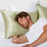 Man sleeping in bed using a pillow in a Silk Pillowcase from Dore and Rose in the color Olive Green