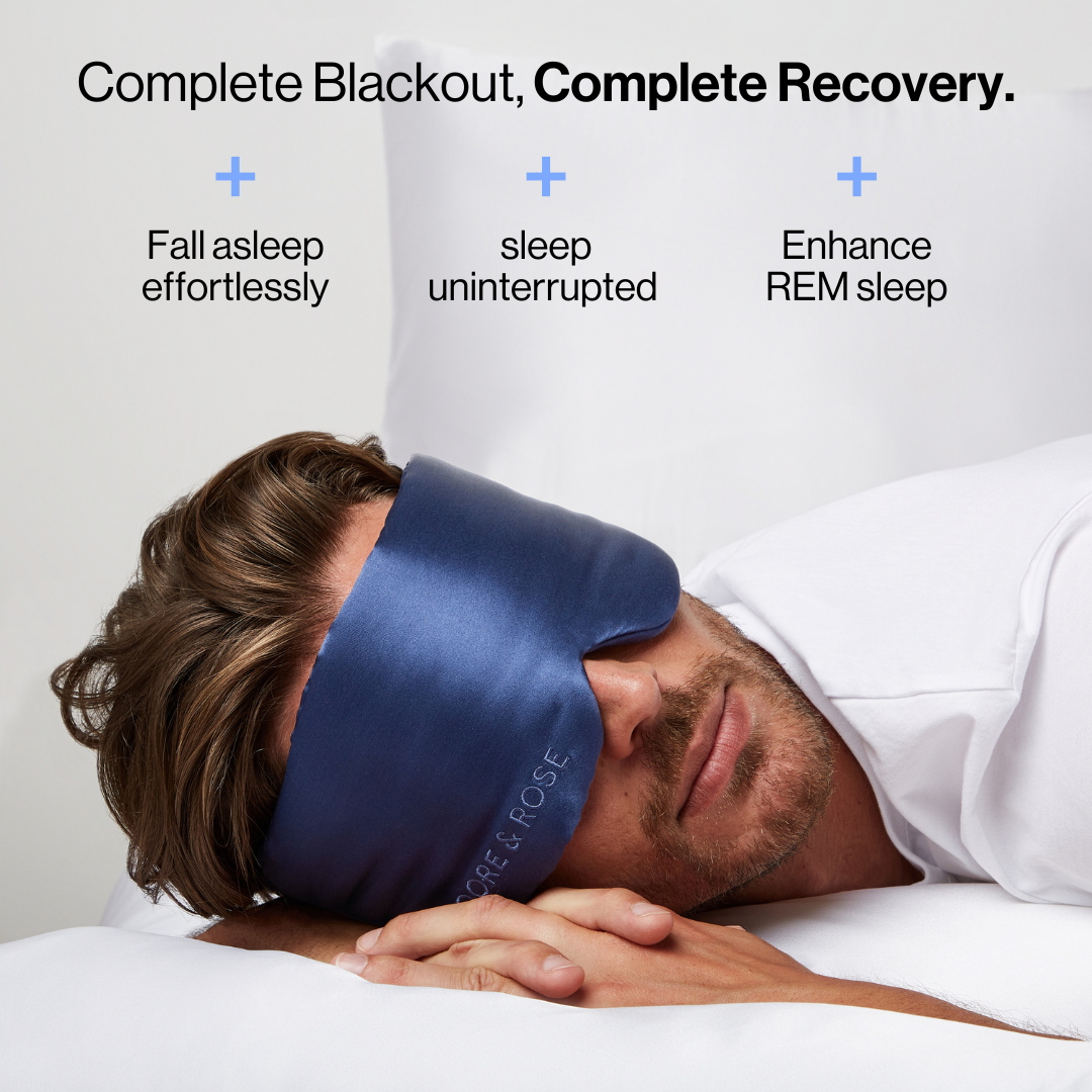 Man sleeping wearing the Dore and Rose Luxury Soft Silk Sleeping Eye Mask in the color navy blue with its benefits written on the top part