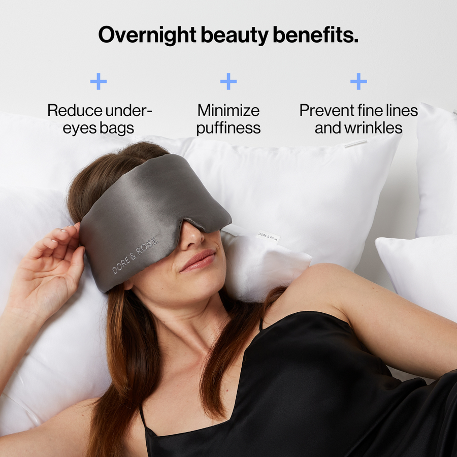 Woman sleeping wearing the Dore and Rose Luxury Soft Silk Sleeping Eye Mask in the color grey with its benefits written on the top part