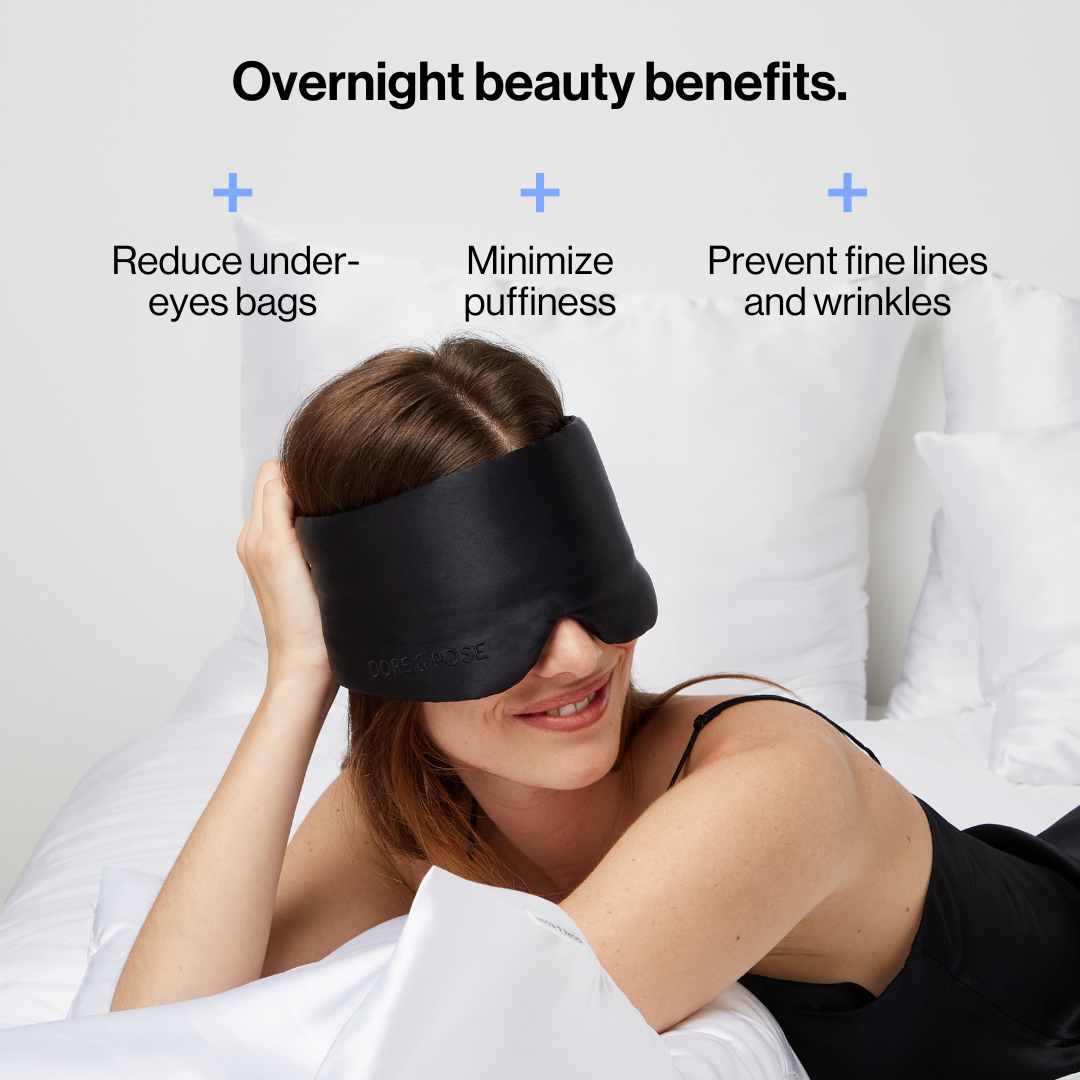 Woman smiling wearing the Dore and Rose Luxury Soft Silk Sleeping Eye Mask in the color black with its benefits written on the top part