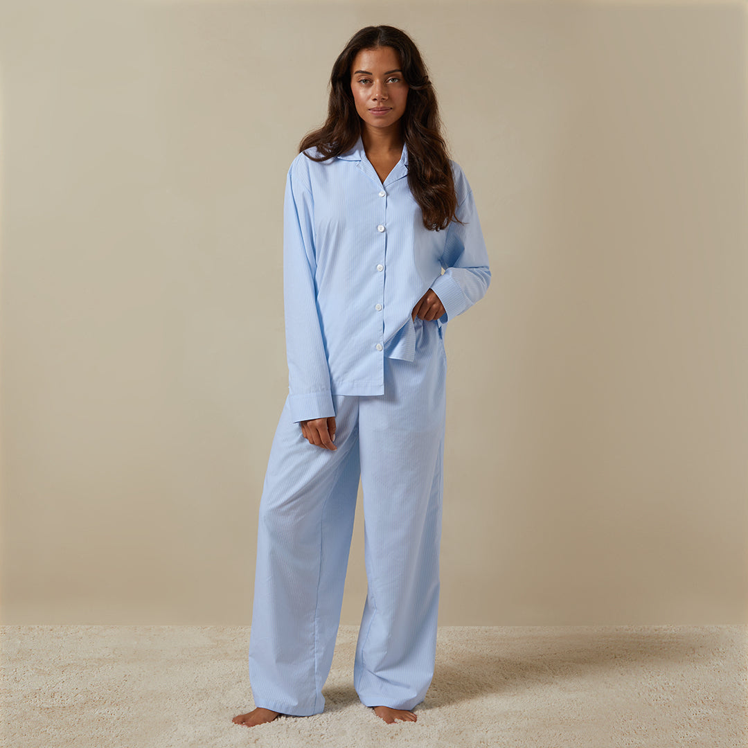 Woman standing wearing the Long Sleeve Striped Pajama Set from Dore and Rose in Blue and White stripes