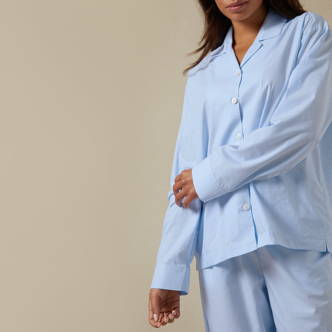 Woman standing wearing the Long Sleeve Striped Pajama Set from Dore and Rose in Blue and White stripes