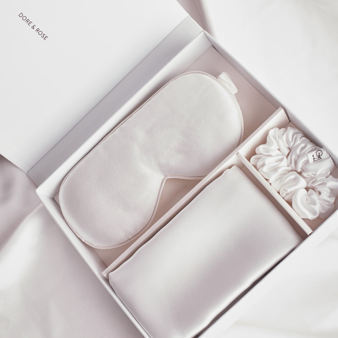 What's in the box of the Dore and Rose Skin Recovering Sleep Bundle in the color white? A Soft Silk Eye Mask for a well rested eyes, Silk Pillowcase for a Luxury feel when you sleep and a Silk Scrunchie to keep your hair in place while maintaining it soft and tangle free