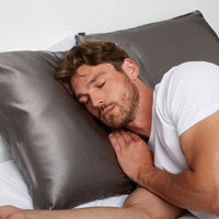 Man sleeping in bed using a  pillow in a Silk Pillowcase from Dore and Rose in the color Gray