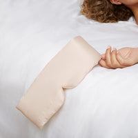 Woman's hand holding a Silk Sleeping Eyemask from Dore and Rose in the Champagne Beige