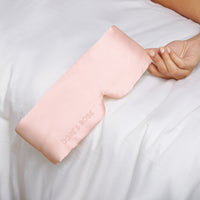 Woman's hand holding a Silk Sleeping Eyemask from Dore and Rose in the color Pink