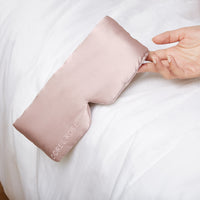 Woman's hand holding a Silk Sleeping Eyemask from Dore and Rose in the color Rose Pink