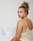 Woman sitting in bed waking up wearing a silk scrunchie from Dore and Rose in the color Olive Green